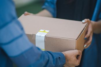 A person is holding a cardboard box with a white label on it.